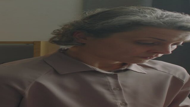 Vertical zoom shot of experienced female doctor using laptop and looking at patient during medical test in clinic