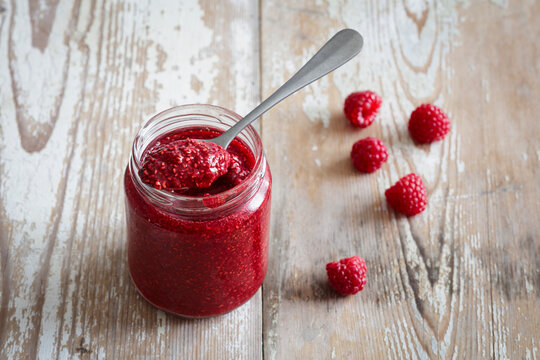 Jar of raspberry jam on wooden surface