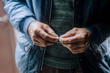 An elderly pensioner man is struggling with smoking addiction, holding a cigarette in his hands. Medicine concept. Photography, portrait.