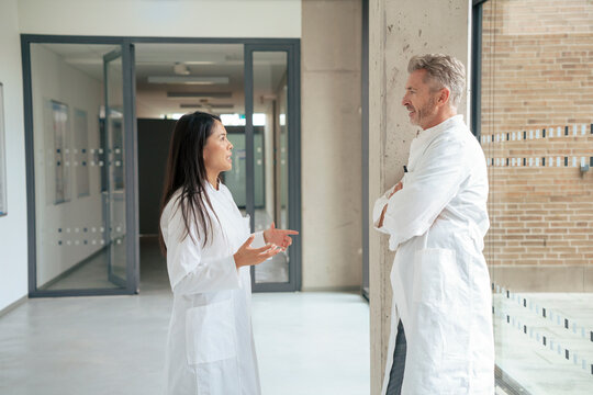 Mature scientist having discussion with colleague in corridor