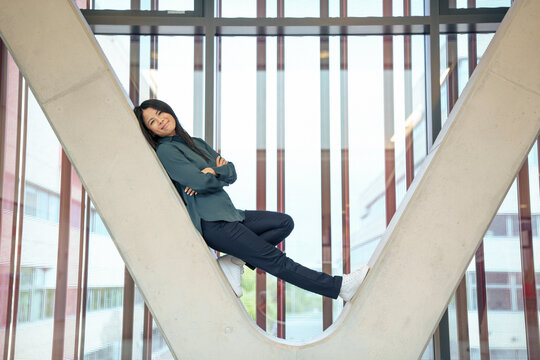 Happy businesswoman leaning on architectural column