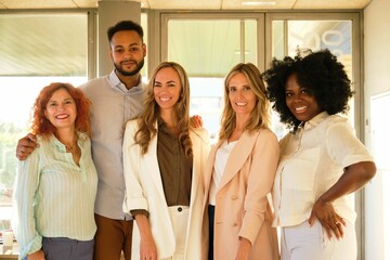 Smiling team of multiethnic businesspeople standing together in a coworking office.
