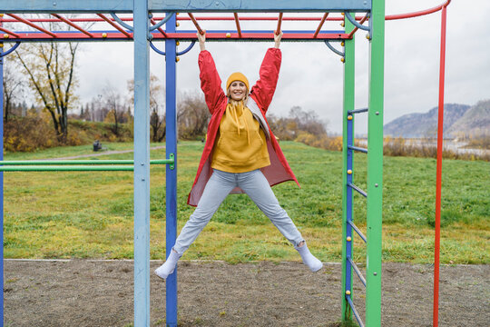 Smiling woman hanging on monkey bars in park