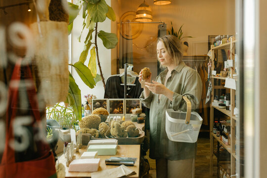 Woman choosing organic bath sponge and shopping in eco-shop