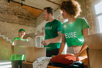 Smiling activists putting clothes in donation boxes at apartment