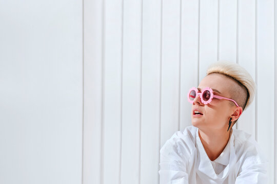 Thoughtful woman wearing funky glasses in front of white wall