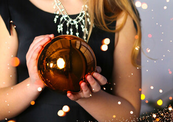Banner with a girl in a black dress holding a golden ball. The interior  with lights. Christmas. Make a wish. Holidays concept