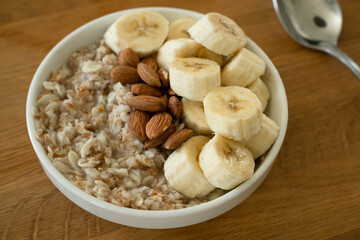 Oatmeal with banana, honey and almonda for breakfast on a table