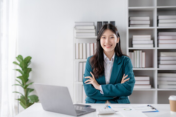 Smiling confident asian businesswoman with arms crossed sitting in office.