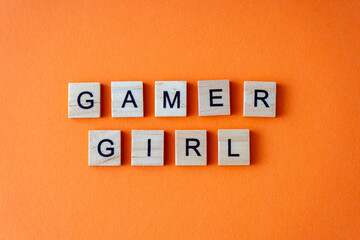 Word gamer girl. The phrase is laid out in wooden letters top view. Orange flat lay background