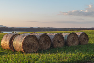 A golden field of hay bales, a serene lake at a sunset.