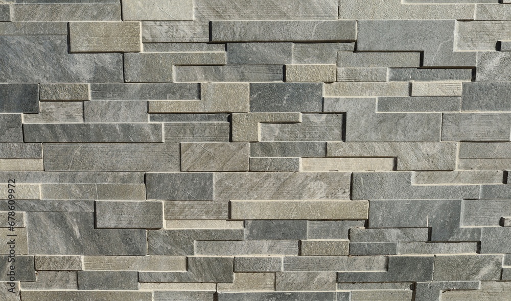 Wall mural Wall paneling made of stone bricks of different shapes. Colors are shades of gray. Background and texture.