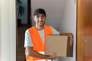 Delivery man delivers package to customer at home. Copy space available. - obrazy, fototapety, plakaty