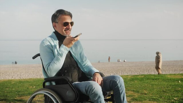 Happy middle aged handsome man activating virtual assistant on mobile phone. Smiling young mixed race man recording answering by audio message in social network.