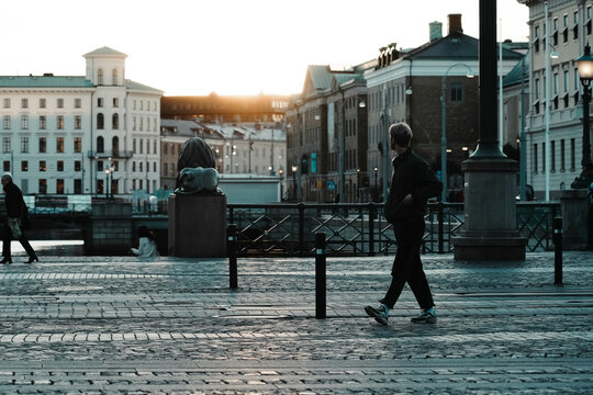 Göteborg, Sweden. People stroll through the streets of the Swedish city at sunset. Passers-by cross the street. Scenes of urban life. Street photography and warm colors of autumn sunset