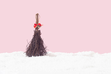 Wooden broom with a jingle bell on the snow. Minimal holiday, winter concept .