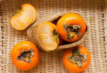 Ripe persimmons. Fresh persimmons on a wicker basket, top view.
​