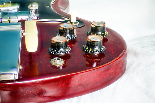 Closeup of guitar tone and volume witch hat knobs with maestro vibrato 1966 on cherry color Gibson SG solid guitar standard, electric musical instrument. old school retro vintage from Kalamazoo plant