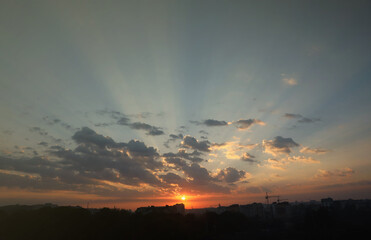 Beautiful sunrise with warm orange sunlight and beams through cloudy blue sky