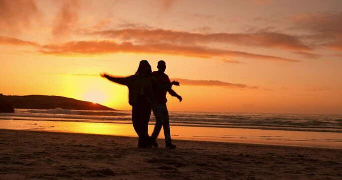 Couple, silhouette and dancing at beach, sunset sky and freedom with moving together, summer and vacation. Man, woman dancer and outdoor with steps, love and holding hands in dusk sunshine by ocean