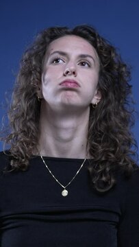 Bored woman taking a deep sigh feeling exhaustion, close-up face of exasperated 20s person losing patience and rolling eyes, vertical video