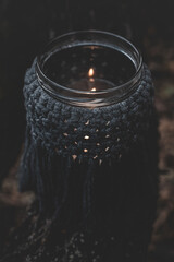 Jar with a burning candle decorated with knitted macrame fabric