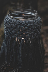 Jar with a burning candle decorated with knitted macrame fabric