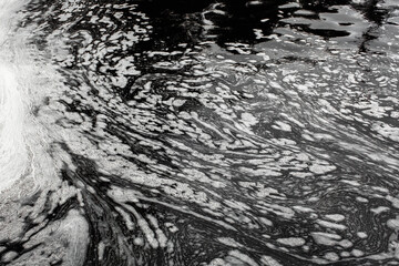 Fototapeta premium Black waste water with white foam on water surface environmental pollution of nature from effluent factory.