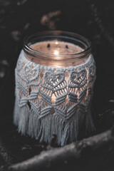 Jar with a burning candle decorated with knitted macrame fabric
