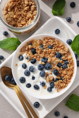 Bowl with yogurt, spoons and jar on light background, top view
