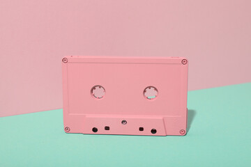 Cassette on green table on pink background, close up