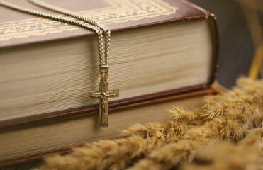 Silver necklace with crucifix cross on christian holy bible book on black wooden table. Asking...