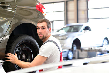 portrait of a friendly car mechanic in the workshop in work clothes - job repair of vehicles