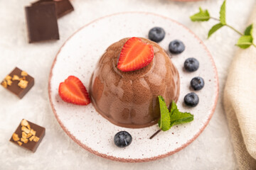 Chocolate jelly with strawberry and blueberry on gray concrete, side view, selective focus.