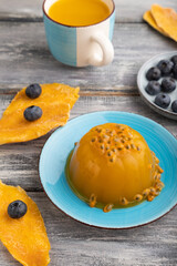 Mango and passion fruit jelly with blueberry on gray wooden, side view.