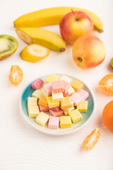 Various fruit jelly chewing candies on white wooden. apple, banana, tangerine, side view, selective focus.