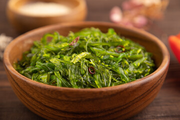 Chuka seaweed salad in wooden bowl on brown wooden. Side view, selective focus