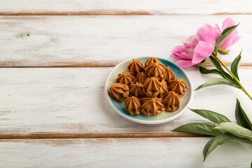 Homemade soft caramel fudge candies on white wooden, side view, copy space.