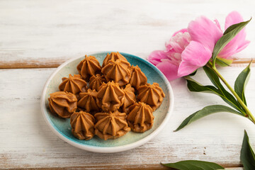 Homemade soft caramel fudge candies on white wooden, side view