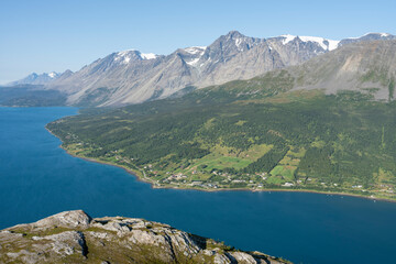 Majestic Lyngen Alps and and a village by the fjord on a sunny summer afternoon, high angel view