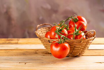 Tomatoes, beautiful arrangement with tomatoes in a basket on rustic wood, selective focus.