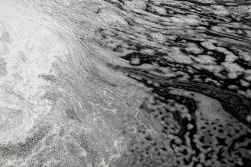 Black waste water with white foam on water surface environmental pollution of nature from effluent factory.