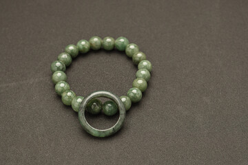 Jade bangle or bracelet and green jade ring on a black background.