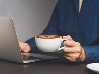 Businesswoman holding a cup of coffee while sitting at the table