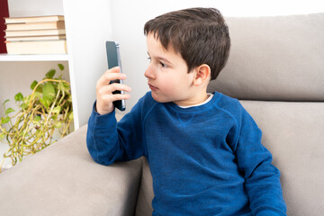 Boy suffering from eyestrain trying to message on a smart phone in the living room