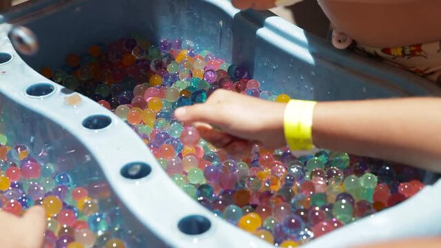 children's hands playing with multicolored gel balls