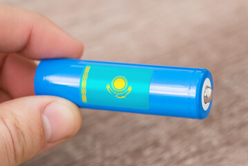 Rechargeable li-ion battery in hand of a man with sticker of Kazakhstan flag. Produce lithium...