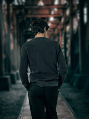 A man walking down a dark alley way, unrecognizable, with hands in his pockets