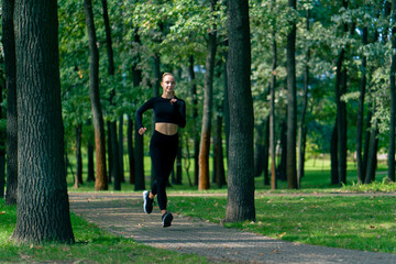 A young girl in sportswear and headphones runs in park in the morning to maintain physical fitness