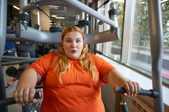 Tired sweaty obese woman breathing hard training at gym